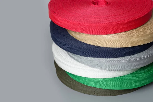 Role textilní pásky na šedém pozadí. výroba barevné pásky. — Stock fotografie