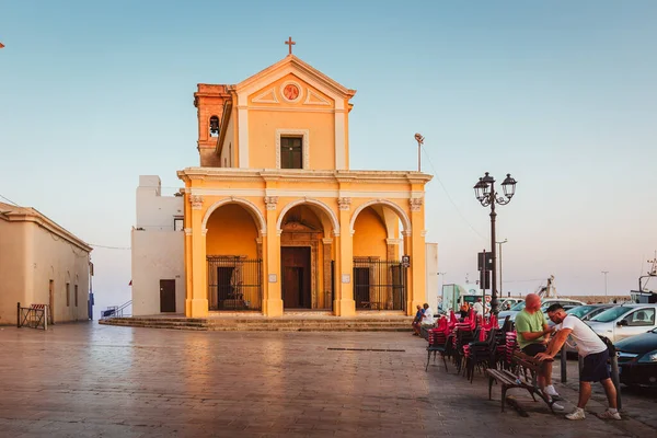 Gelibolu, Lecce - 8 Ağustos 2025: Aziz Meryem Kilisesi önündeki meydanı ziyaret eden turistler, tarihi barok mimarisi ile yaz günbatımında aydınlatılıyor.
