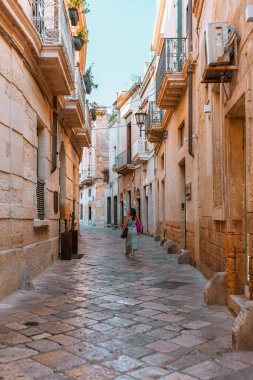 Lecce, Puglia - 11 Ağustos 2025: Barok binalı Roma harabelerinin sahne kompozisyonu, Lecce 'nin bir yaz akşamında katmanlanmış tarih ve kültür mirasını sergilemesi.