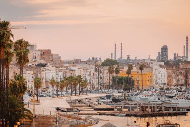 Taranto, İtalya - 16 Ağustos 2025: Taranto Limanı üzerinde balıkçı tekneleri, kentsel binalar ve sakin yaz denizi.