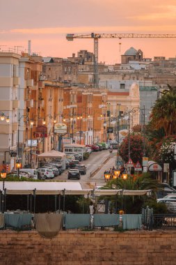 Taranto, İtalya - 16 Ağustos 2025: Gün batımında Taranto 'da canlı kıyı evleri ve denizde balıkçı tekneleri manzarası.