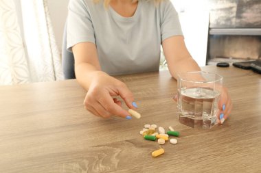 Evde tedavi için vitamin ya da hap alan bir kadın. Kadın vitamin ve takviye alıyor. Tıbbi konsept.