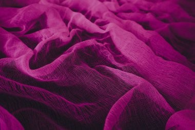Yumuşak kıvrımları ve ince ağ dokusuyla canlı pembe tekstil. Kırışık deseni olan soyut kumaş arkaplan tasarım, moda veya dekoratif projeler için uygun.