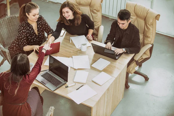 Young people do business or organize a startup together communicating in a loft-style room