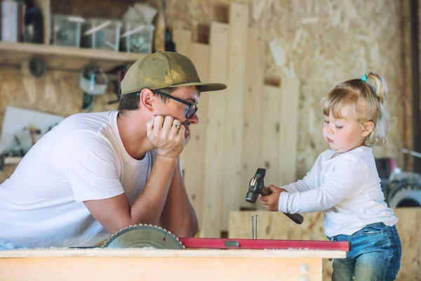 Young happy family dad and baby in the carpentry workshop workin