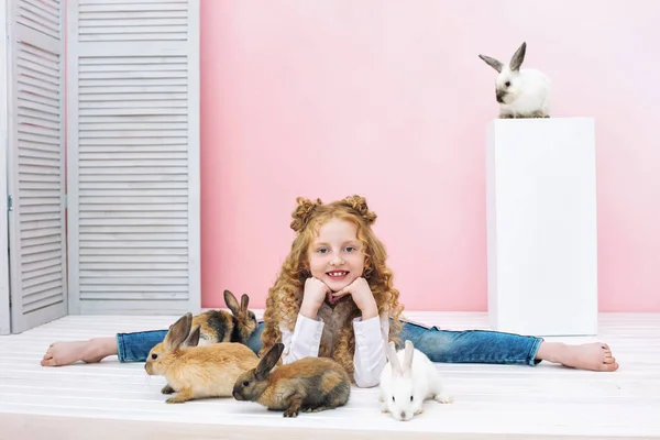 Beautiful child girl with curly hair and with fluffy animals rab