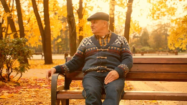 Oude man zit op de Bank in het najaar park — Stockfoto