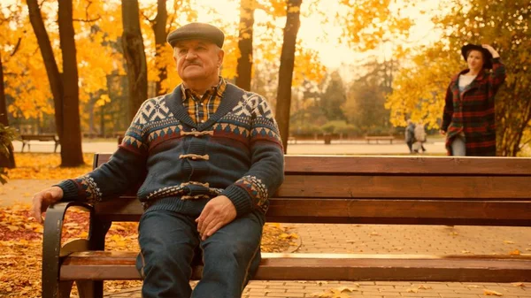 Velho está esperando por sua filha no parque de outono — Fotografia de Stock