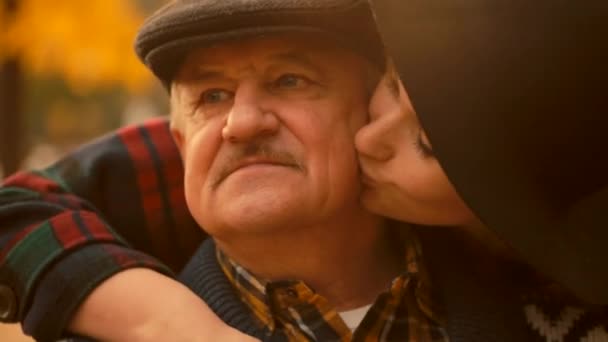 Jovem está beijando sua bochecha pai sênior na reunião no parque de outono — Vídeo de Stock
