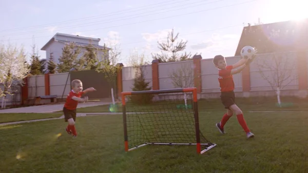 Malí kluci hrají fotbal na trávníku v zahradě — Stock fotografie