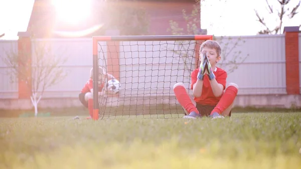 Malí kluci sedí u fotbal gól na trávníku — Stock fotografie