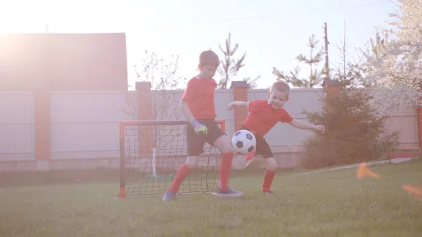 Malí kluci hrají fotbal na trávníku v zahradě — Stock fotografie