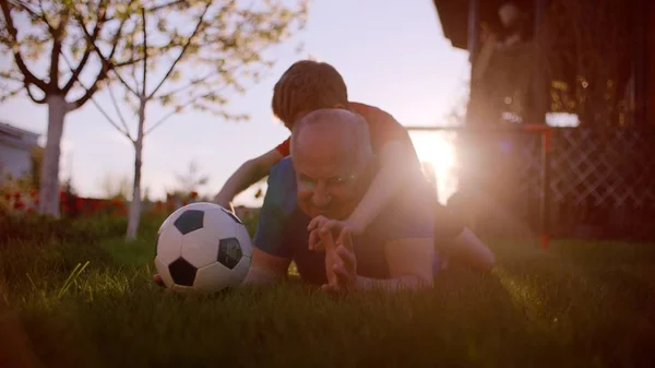 小さな男の子と芝生の上のサッカー ボールを持って彼の祖父 — ストック写真