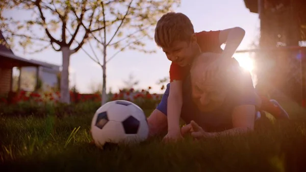 おじいちゃんと孫は、芝生の上、日没時、サッカーを遊んでいます。 — ストック写真