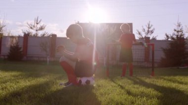 Küçük çocuklar arka bahçe'nın bahçesinde futbol oynadıktan sonra üzgün değildir