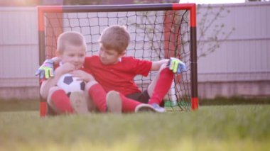 Küçük çocuklar futbol gol çimenlerin üstünde oturuyor