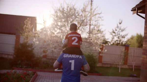 Retrato del abuelo con su nieto en el cuello con pelota de fútbol —  Fotos de Stock