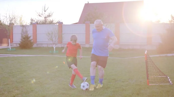 Dědeček hrál fotbal se svým vnukem na trávníku u dvorku — Stock fotografie