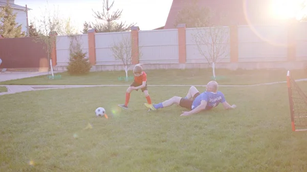 祖父は裏庭の芝生の上で彼の孫とサッカーをしています — ストック写真