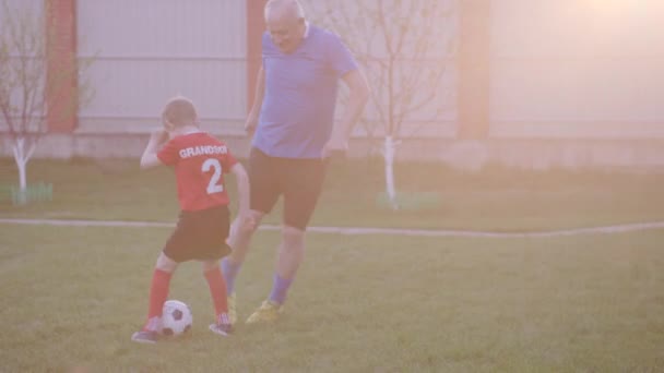 Glücklicher alter Mann mit seinen Enkeln beim Fußballspielen — Stockvideo