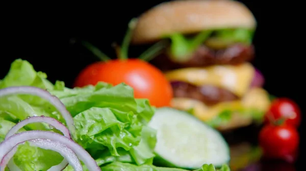 Primer plano de verduras frescas y deliciosa hamburguesa en el fondo fuera de foco —  Fotos de Stock