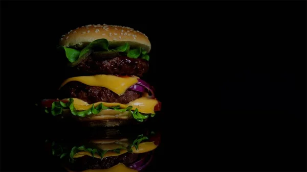 Burger lezat dengan daging sapi, keju dan sayuran di latar belakang cermin hitam untuk komersial — Stok Foto