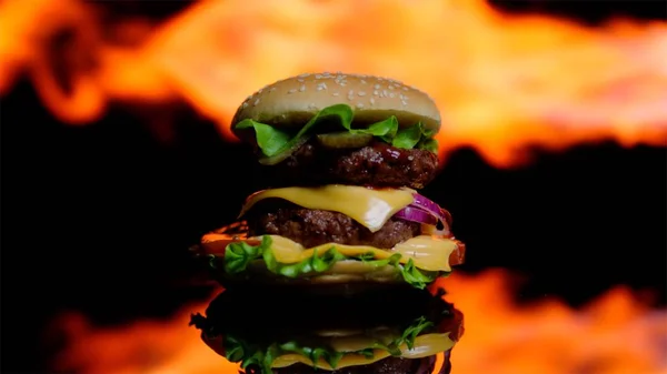Alev içinde pişirme siyah ayna yüzeyinde lezzetli burger