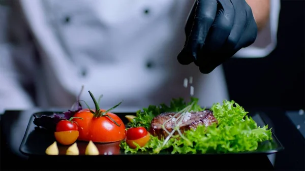 Şef yavaş yemek için tuz ekleyerek. Arka planda yak²n şef olduğunu