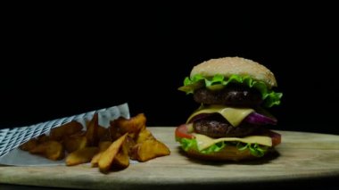 Çift peynir ve patates kızartması ile lezzetli burger kapatın. Siyah arka plan