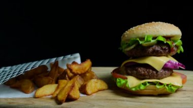 Çift peynir ve patates kızartması ile lezzetli burger kapatın. Siyah arka plan