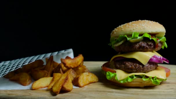 Close up de delicioso hambúrguer com queijo duplo e batatas fritas. Fundo preto — Vídeo de Stock