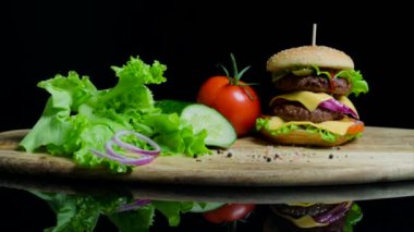 Taze sebze ve siyah arka plan üzerine peynir ve sığır pirzolası lezzetli burger