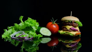 Taze sebze ve siyah arka plan üzerine peynir ve sığır pirzolası lezzetli burger