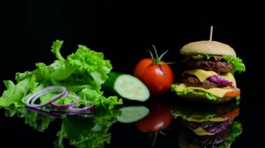 Taze sebze ve siyah arka plan üzerine peynir ve sığır pirzolası lezzetli burger