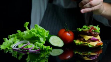 Sığır eti, peynir ve sebze ile lezzetli burger bitirme Şef. Ticari için siyah arka plan