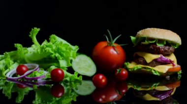 Taze sebze ve siyah arka plan üzerine peynir ve sığır pirzolası lezzetli burger