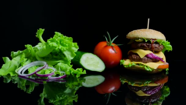 Verduras frescas y sabrosa hamburguesa con queso y chuletas de res en el fondo negro — Vídeos de Stock