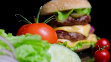 Taze yeşillik ve lezzetli burger yakın çekim. Ticari kullanım için siyah arka plan