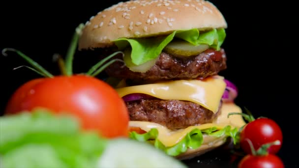 Közelről a friss zöldek és ízletes burger. Fekete háttér részére kereskedelmi használ — Stock videók