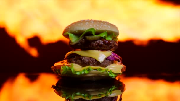 Délicieux hamburger sur la surface miroir noir. La flamme de la grille sur le fond hors foyer — Video