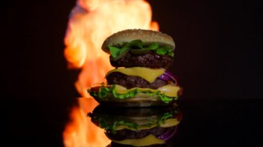 Lezzetli sıcak burger siyah ayna yüzeyi yanıyor. Ticari için siyah arka plan