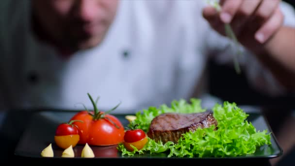 Lo chef sta finendo il delizioso piatto di manzo con verdure. Lo chef è fuori fuoco sullo sfondo — Video Stock