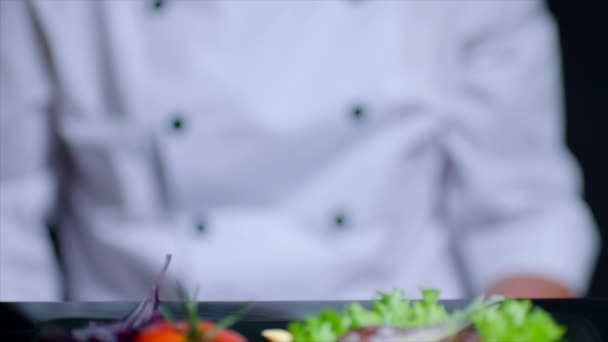 Chef is adding salt to the dish in slow motion. Chef is out of focus on the background — Stock Video