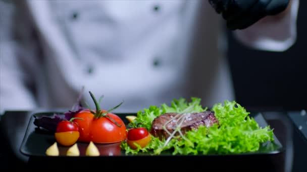 Chef is adding salt to the dish in slow motion. Chef is out of focus on the background — Stock Video