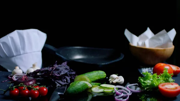 Ainda vida de cozinheiro-fogões cozinha na superfície de espelho preta. Panela, faca, legumes frescos e ingredientes para prato — Fotografia de Stock