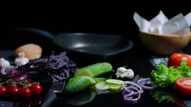Still life of chefs table on black surface. Pan, knife, fresh vegetables and ingredientes for dish — Stock Video