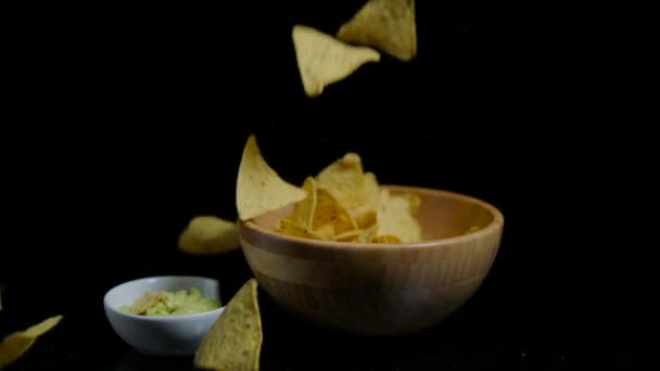 Slow motion Crispy nachos is falling into the wooden bawl. Black background — Stock Video