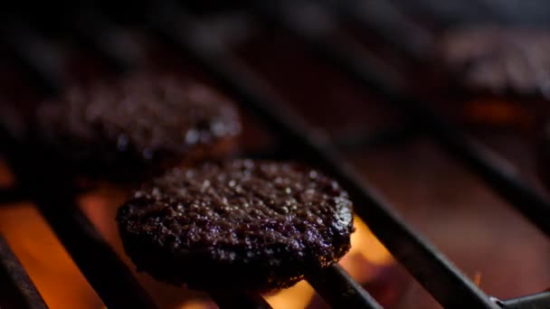 Primer plano de chuletas de hamburguesa en la parrilla con llamas de fuego, cámara lenta — Vídeo de stock