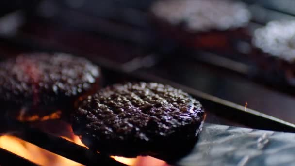 Primo piano di braciole hamburger alla griglia con fiamme di fuoco, chef li gira, rallentatore — Video Stock