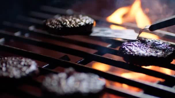Крупный план бургерных отбивных на гриле с огненным пламенем, шеф-повар переворачивает их, замедленное движение — стоковое видео